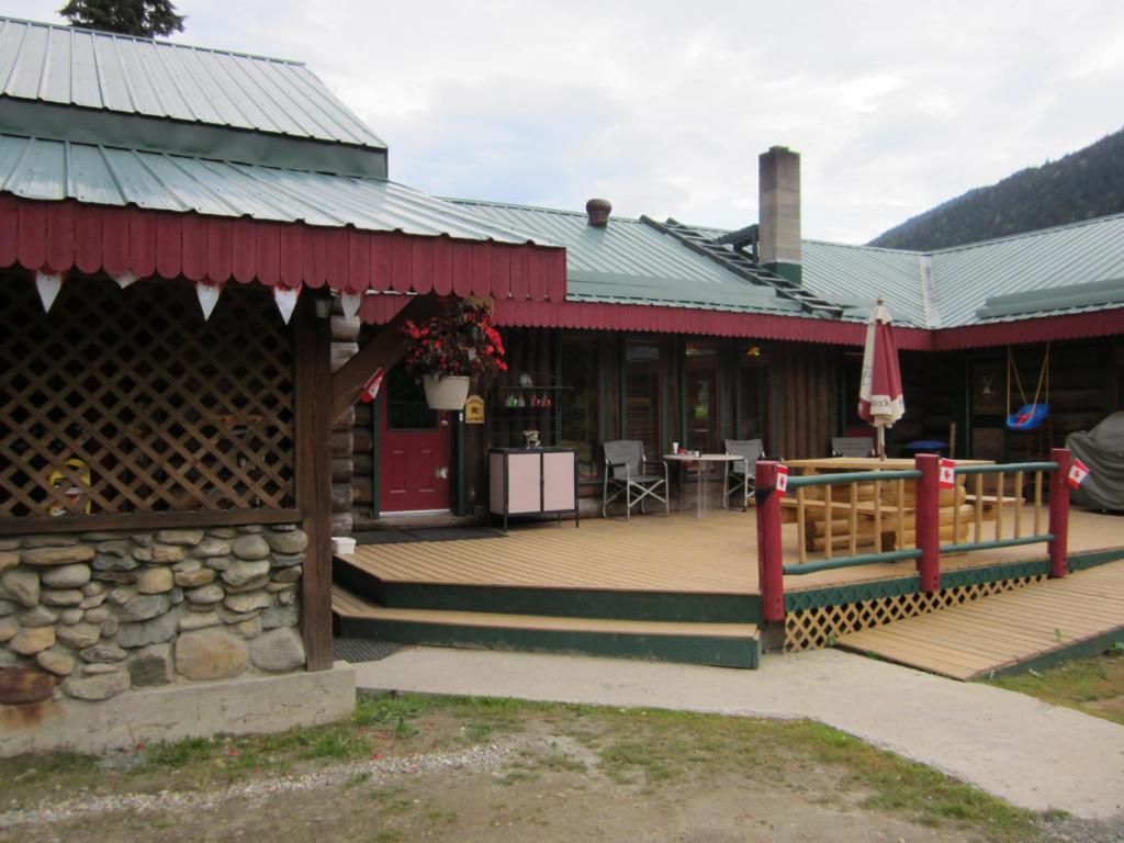 um edifício com um deque com uma mesa e um pátio em Summit River Lodge & Campsites em Valemount