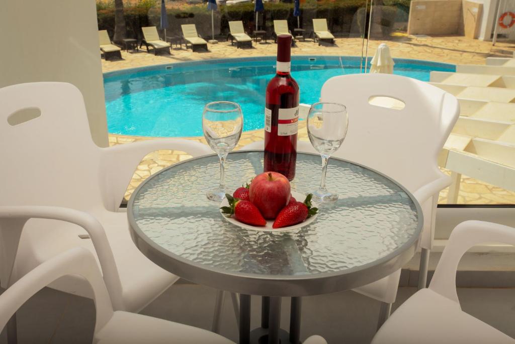 a glass table with two wine glasses and a bowl of fruit at Bellini Hotel in Ayia Napa
