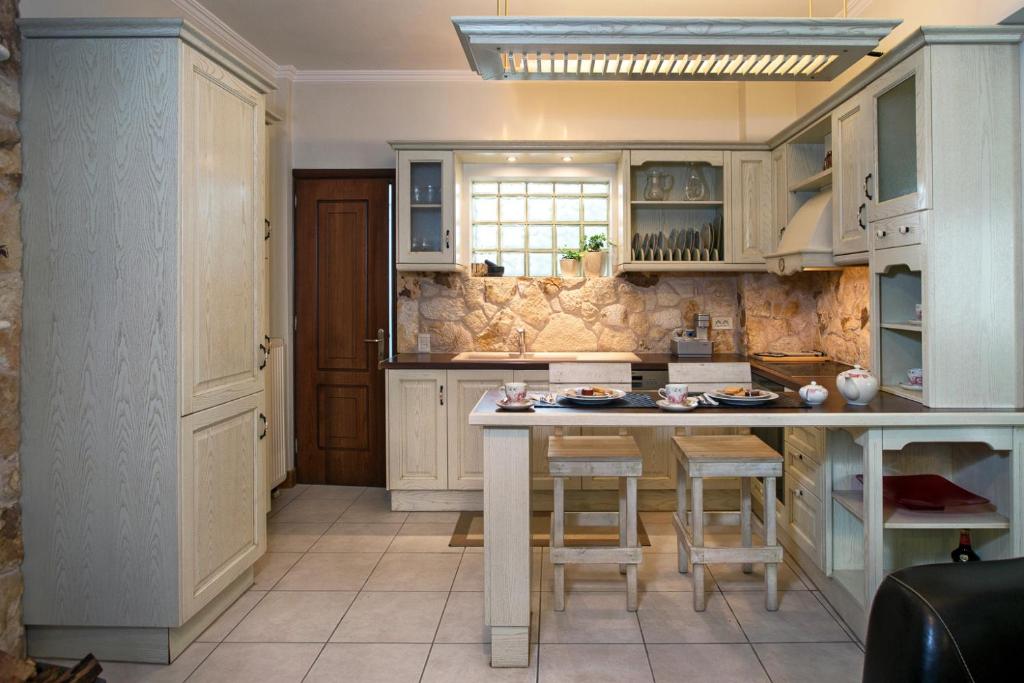 a kitchen with white cabinets and a island with stools at My Apartment Corfu in Potamós