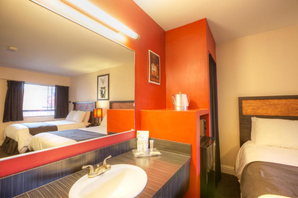a bathroom with a sink and a bedroom with two beds at Hotel Ruby in Spokane