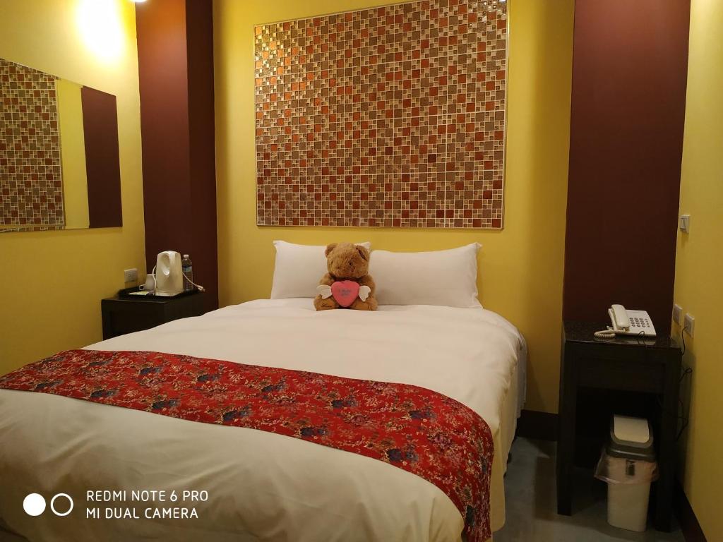 misia siedzącego na łóżku w pokoju hotelowym w obiekcie Sun Moon Lake Crown Yu Hotel w mieście Yuchi