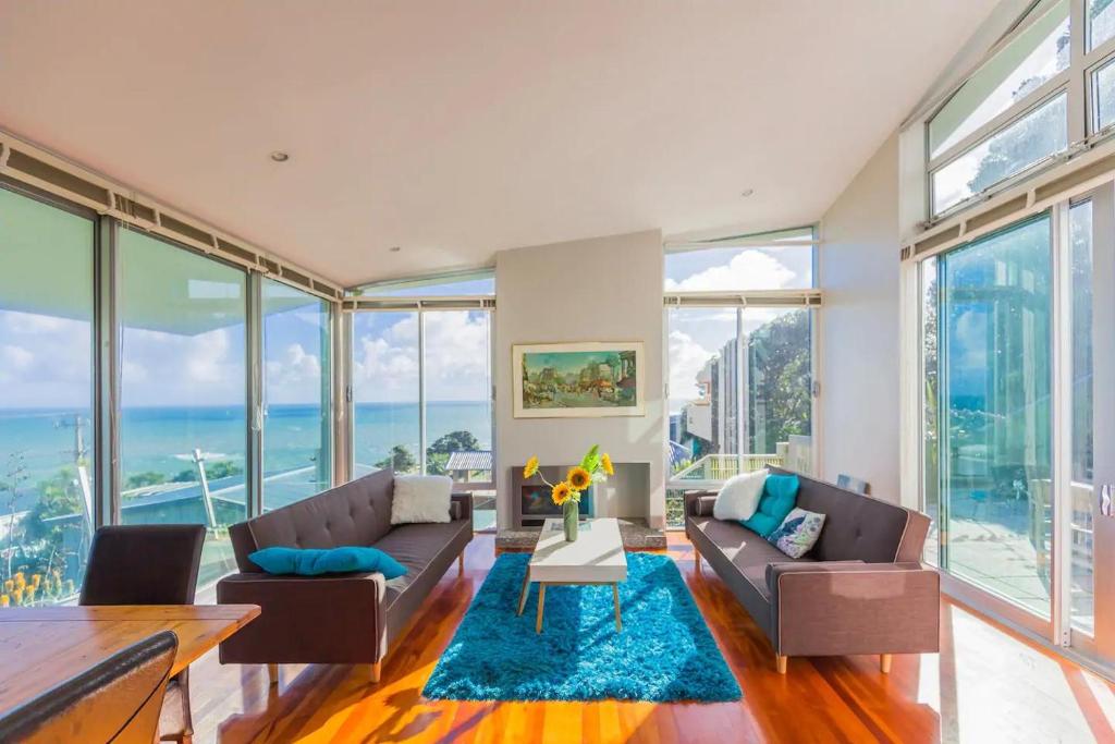uma sala de estar com dois sofás e um tapete azul em Exclusive Sanctuary on the West Coast em Muriwai Beach