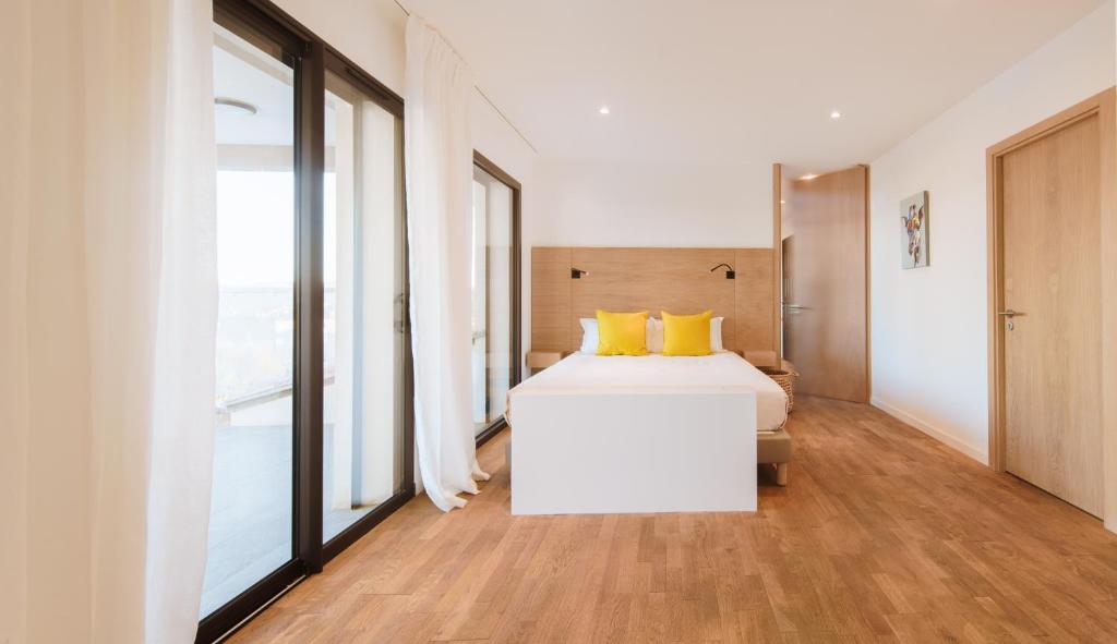 a bedroom with a white bed and large windows at Citta di Lume Suites &amp; Lofts in Porto-Vecchio
