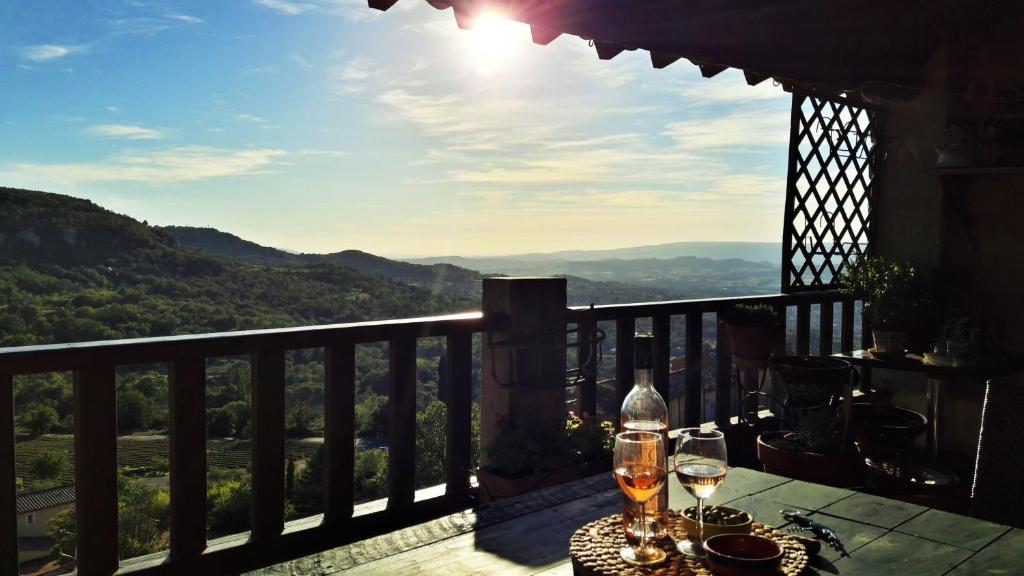 - une table avec des verres à vin sur un balcon avec vue dans l'établissement Entre Terre et Ciel., à Saignon
