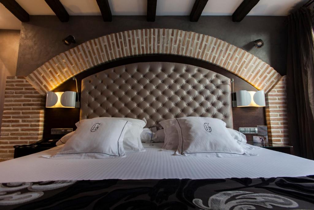 a large bed with a large padded headboard in a bedroom at Hotel Pintor El Greco in Toledo