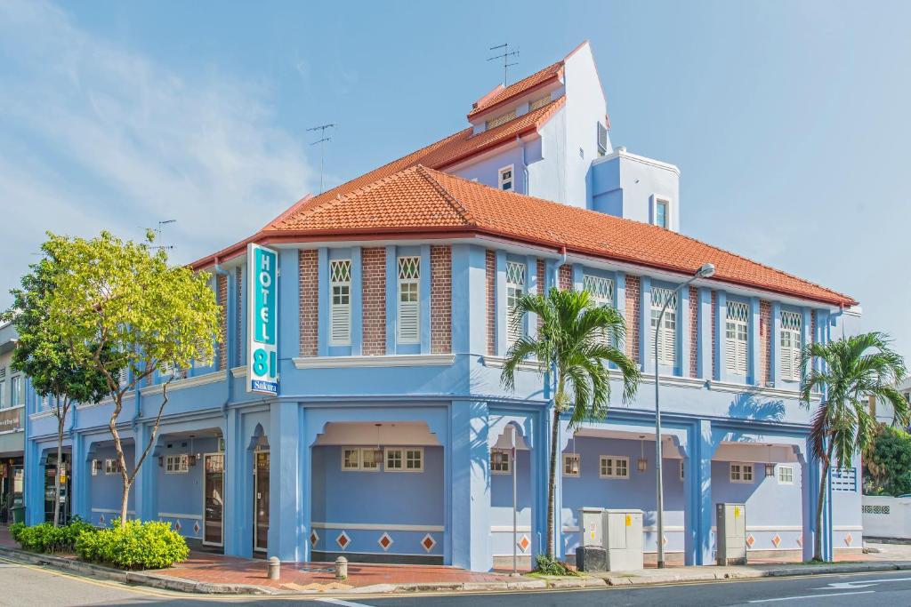 um edifício azul e branco com palmeiras em frente em Hotel 81 Sakura em Singapura