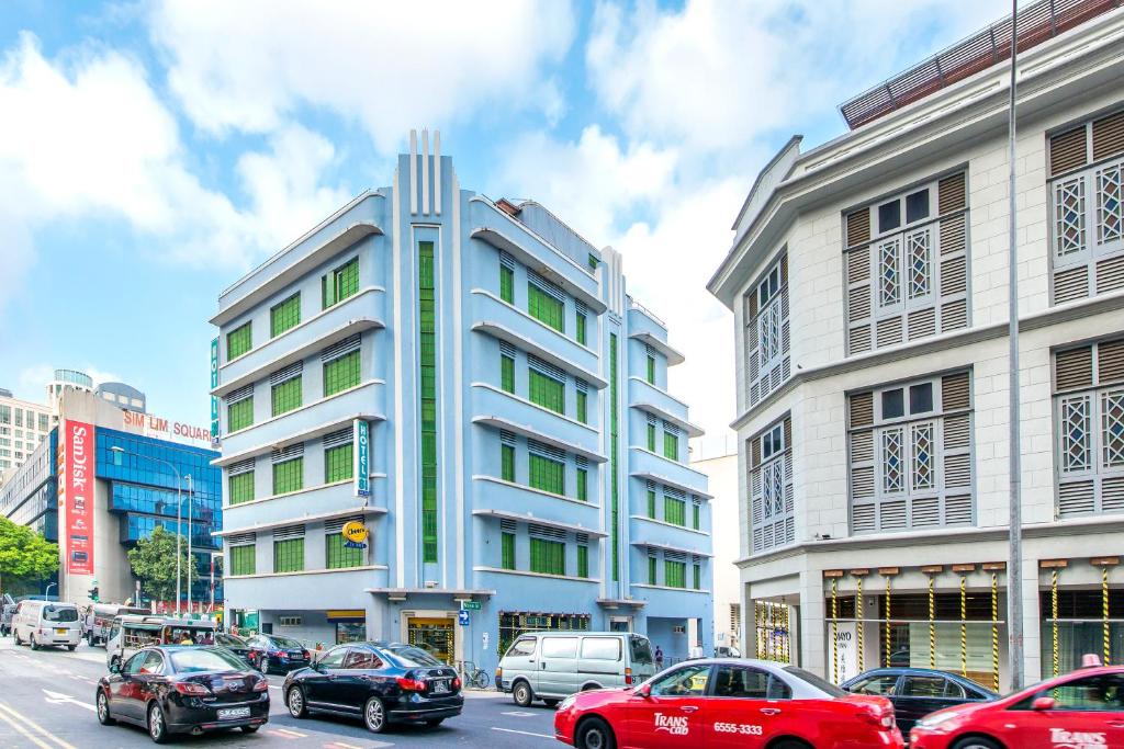 un grand bâtiment blanc avec des voitures garées devant lui dans l'établissement Hotel 81 Rochor, à Singapour