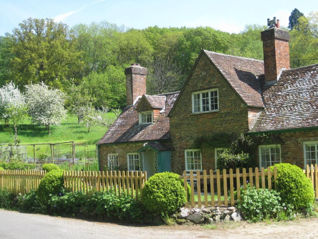 ein altes Backsteinhaus mit einem Holzzaun in der Unterkunft Job's Mill Cottage in Warminster