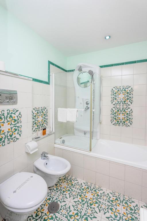 a bathroom with a toilet and a tub and a sink at Hotel Bonadies in Ravello