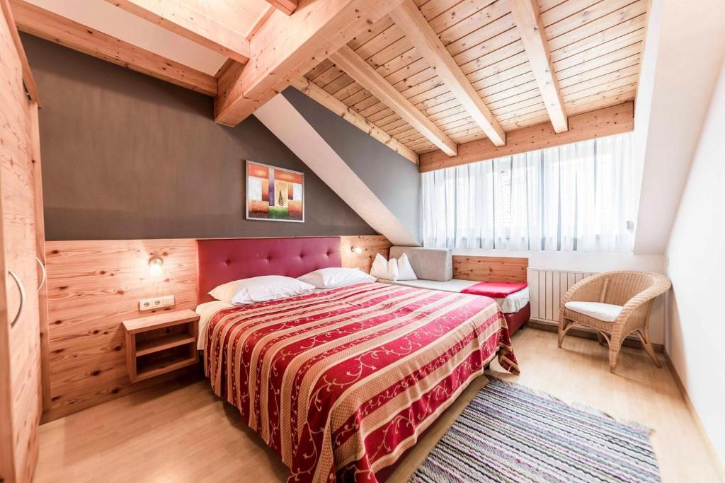 sypialnia z dużym łóżkiem i drewnianym sufitem w obiekcie Appartement Haidacher w mieście San Candido