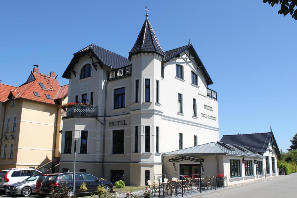 a large white building with a tower on a street at Hotel Villa Sommer in Bad Doberan