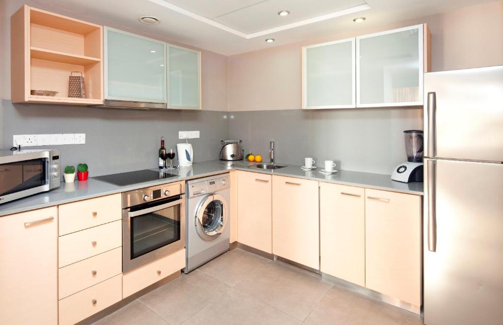 a kitchen with white cabinets and a washer and dryer at Capital Coast Resort And Spa in Paphos