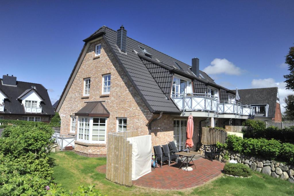 een groot bakstenen huis met een balkon op een tuin bij Appartement Nordseesonne in Wenningstedt