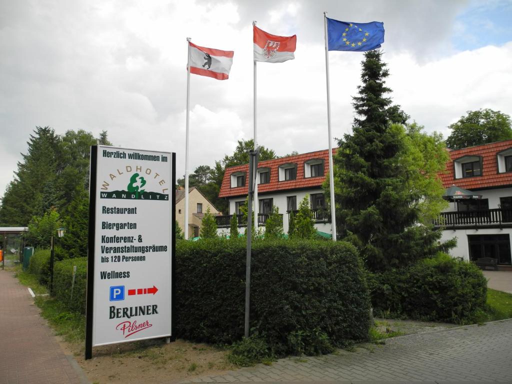 a sign with three flags in front of a building at Waldhotel Wandlitz in Wandlitz