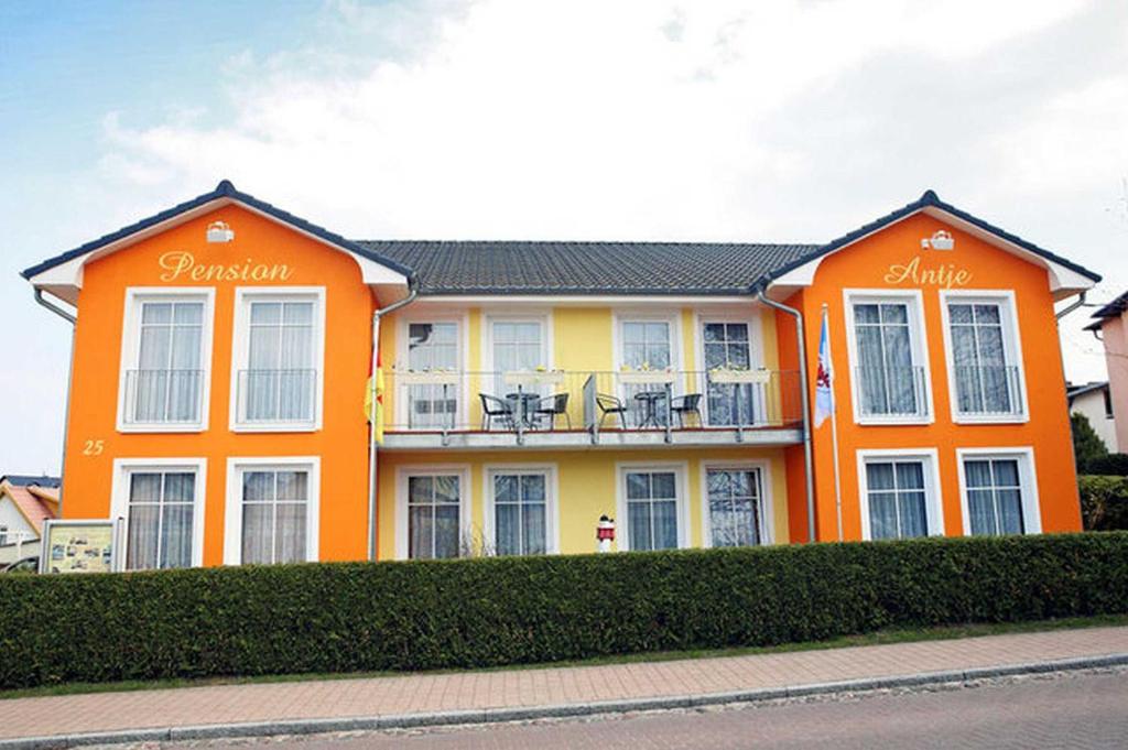an orange building with chairs on a balcony at Pension Haus Antje in Ahlbeck