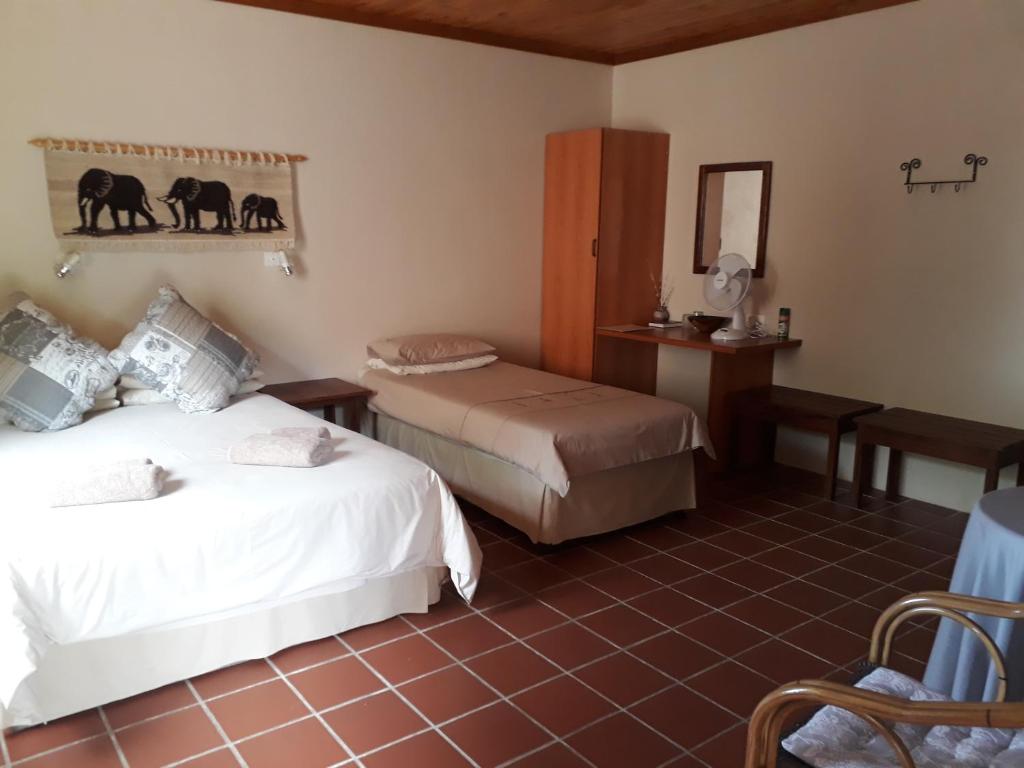 ein Hotelzimmer mit 2 Betten und einem Spiegel in der Unterkunft Buschberg guest farm in Outjo