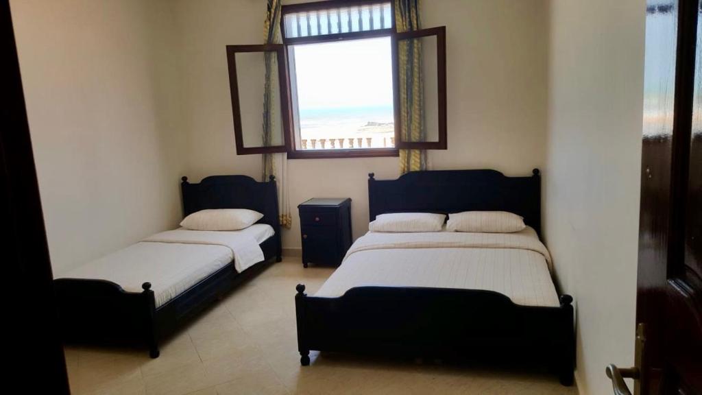 two beds in a room with a window at HOTEL BEACH CLUB LEGZIRA in Sidi Ifni