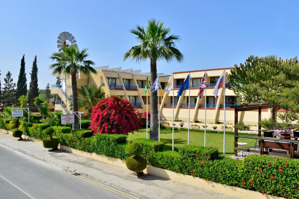 ein Gebäude mit Palmen und Blumen vor einer Straße in der Unterkunft Napa Prince Hotel Apts in Ayia Napa