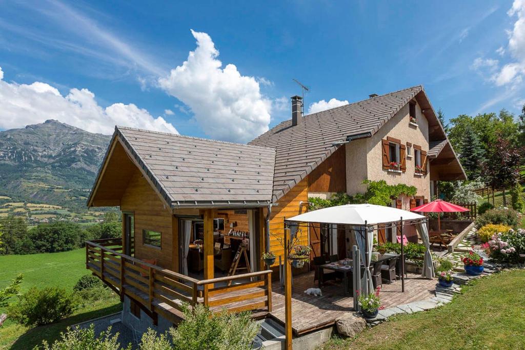 uma pequena casa com uma mesa e um guarda-chuva em "La Coustille" Chambres et Table d'Hôtes em Saint-Léger-les-Mélèzes