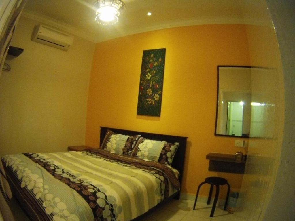a bedroom with a bed and a yellow wall at My 2nd Home in Malacca