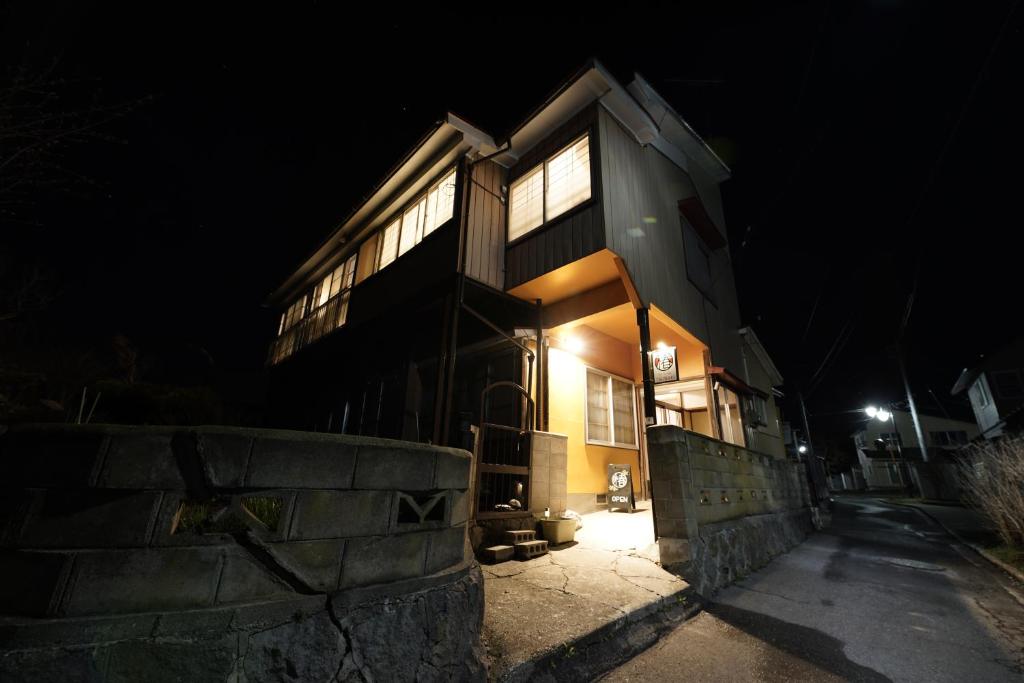 una casa por la noche con las luces encendidas en Tsubaki - the best guesthouse in Inawashiro -, en Inawashiro