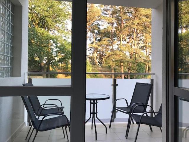 a balcony with a table and chairs and a table and a window at Apartament bursztynowy in Jantar