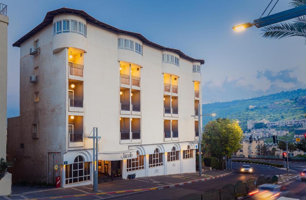 un grand bâtiment blanc au coin d'une rue dans l'établissement Jacob Tiberias by Jacob Hotels, à Tibériade