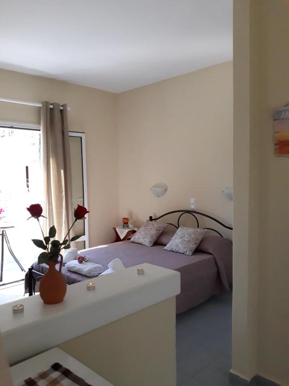 Un dormitorio con una cama y un jarrón con flores. en Studio Vasilis, en Ýpsos