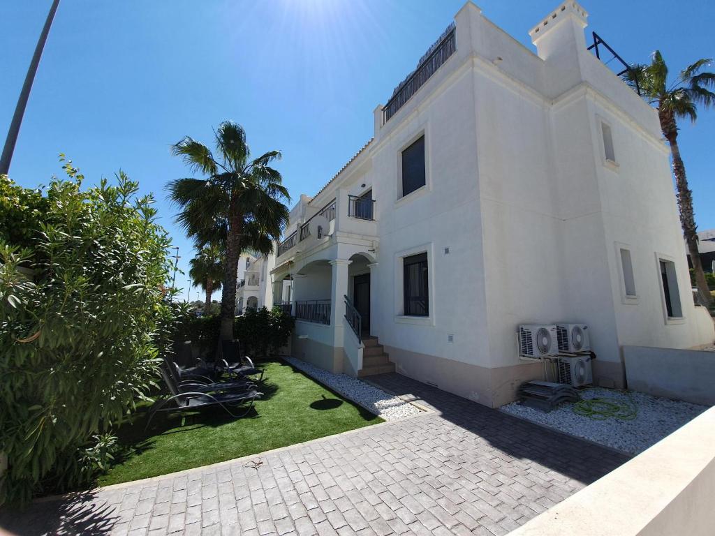 a white house with palm trees in front of it at Eva's Place Villamartin VM052 in Villamartin