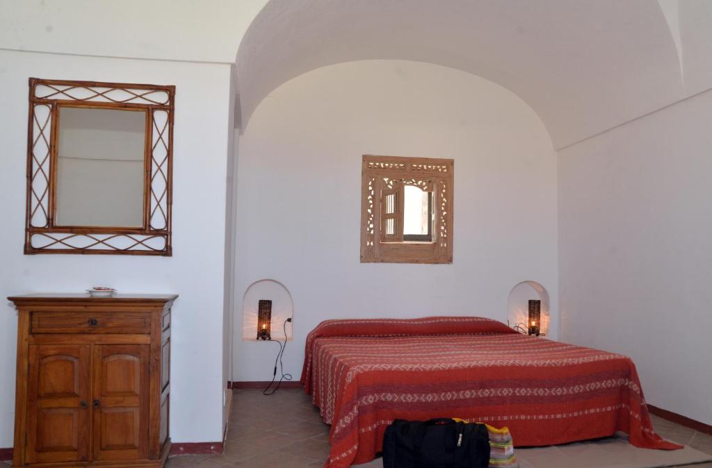 a bedroom with a bed and a dresser and a mirror at I Dammusi Sapori di Pantelleria in Pantelleria
