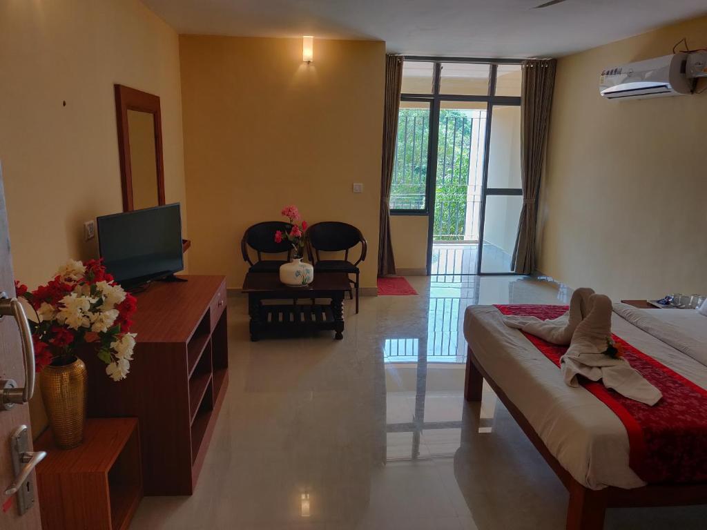 a hotel room with a bed and a tv and a room at Paradise Wild Hills Kodachadri in Kollūru