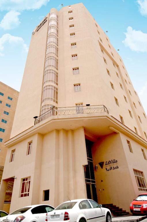 due auto parcheggiate di fronte a un edificio di La Villa Hotel a Doha