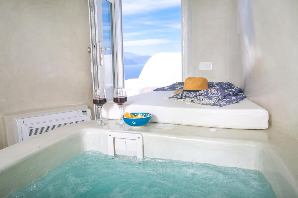 a bathroom with a bath tub with a mirror at White Cave House in Oia