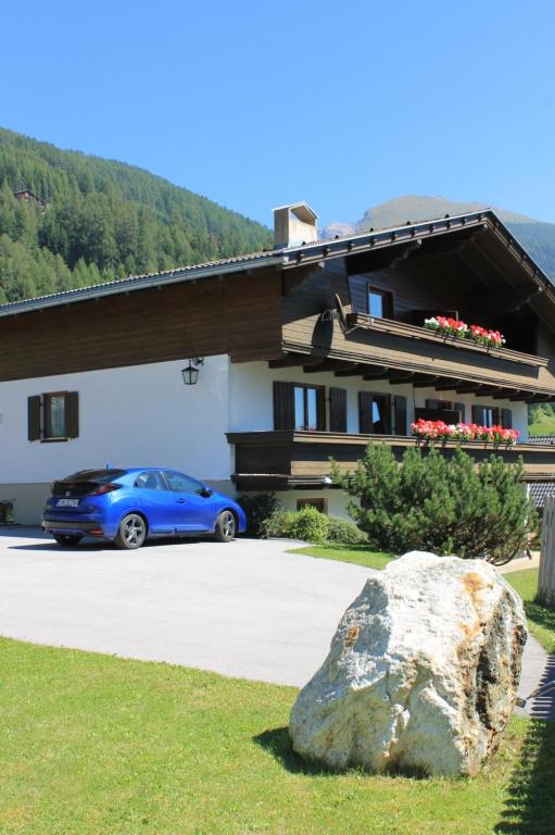a blue car parked in front of a building with a rock at AppHaus Sonne in Heiligenblut
