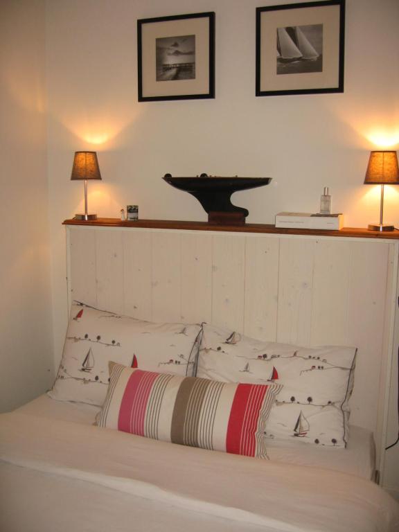 a bed with a white headboard with two lamps at Les jardins du vivier in Combrit