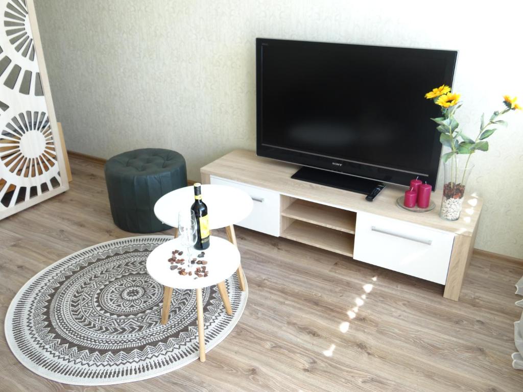 een woonkamer met een televisie en een witte tafel bij Kaštonų apartamentai in Klaipėda
