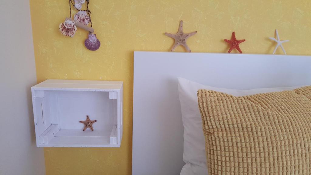 a white box with starfish on a wall next to a pillow at A Casa dos Avós in Nazaré