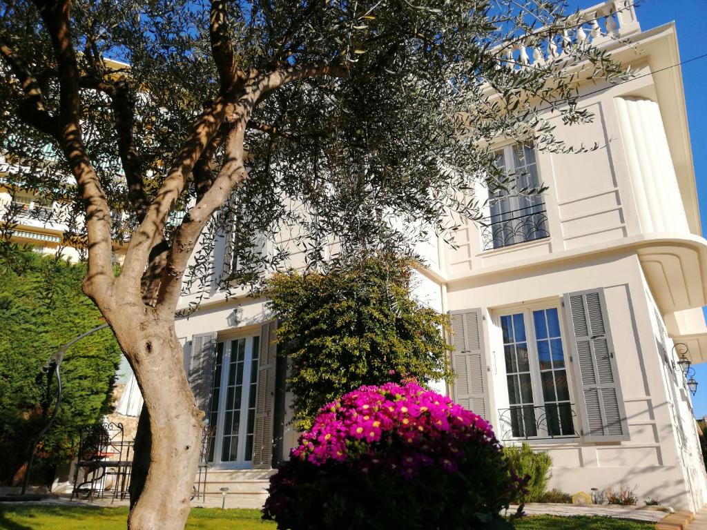 une maison blanche avec des fleurs roses devant elle dans l'établissement B&B Villa Blanche, à Cannes