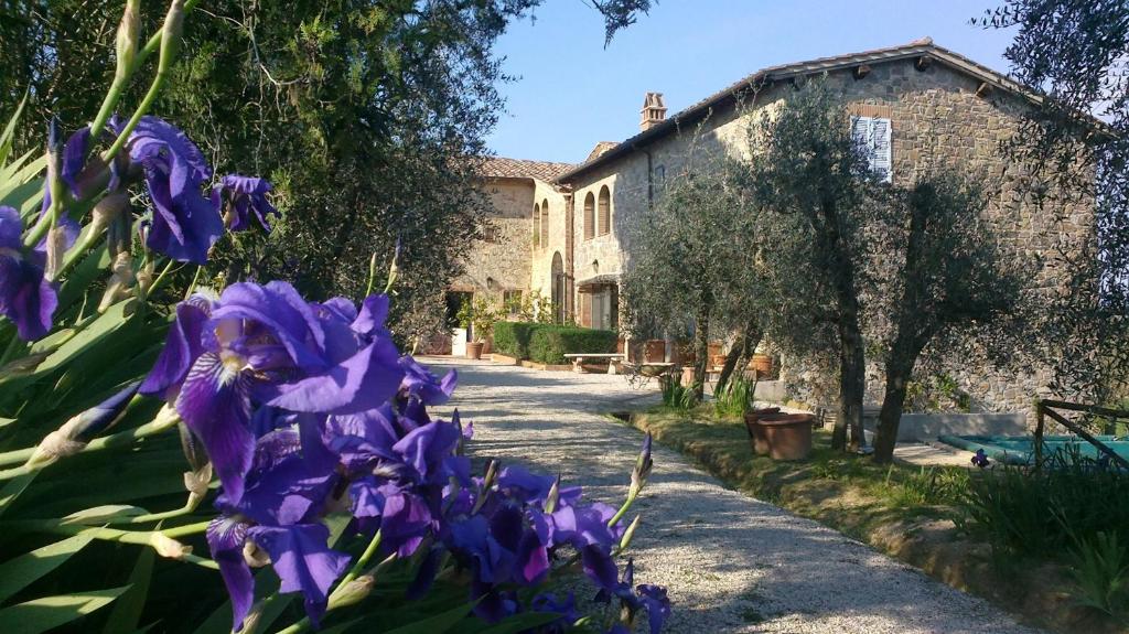 a garden with purple flowers in front of a building at Podere San Quirico in Castelnuovo Berardenga