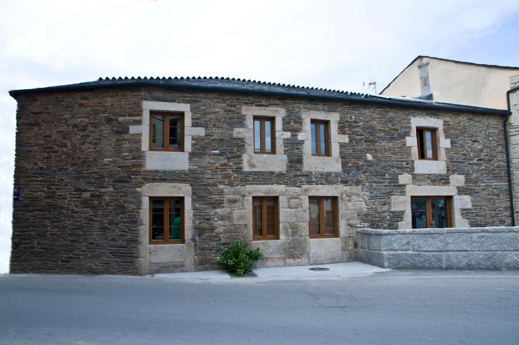 een groot bakstenen gebouw met ramen aan een straat bij PENSION SERRANO in Sarria