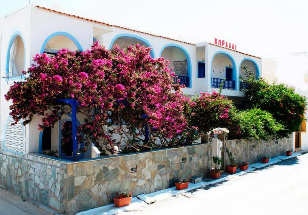 a building with pink flowers on a stone wall at Koralli Studios in Korissia
