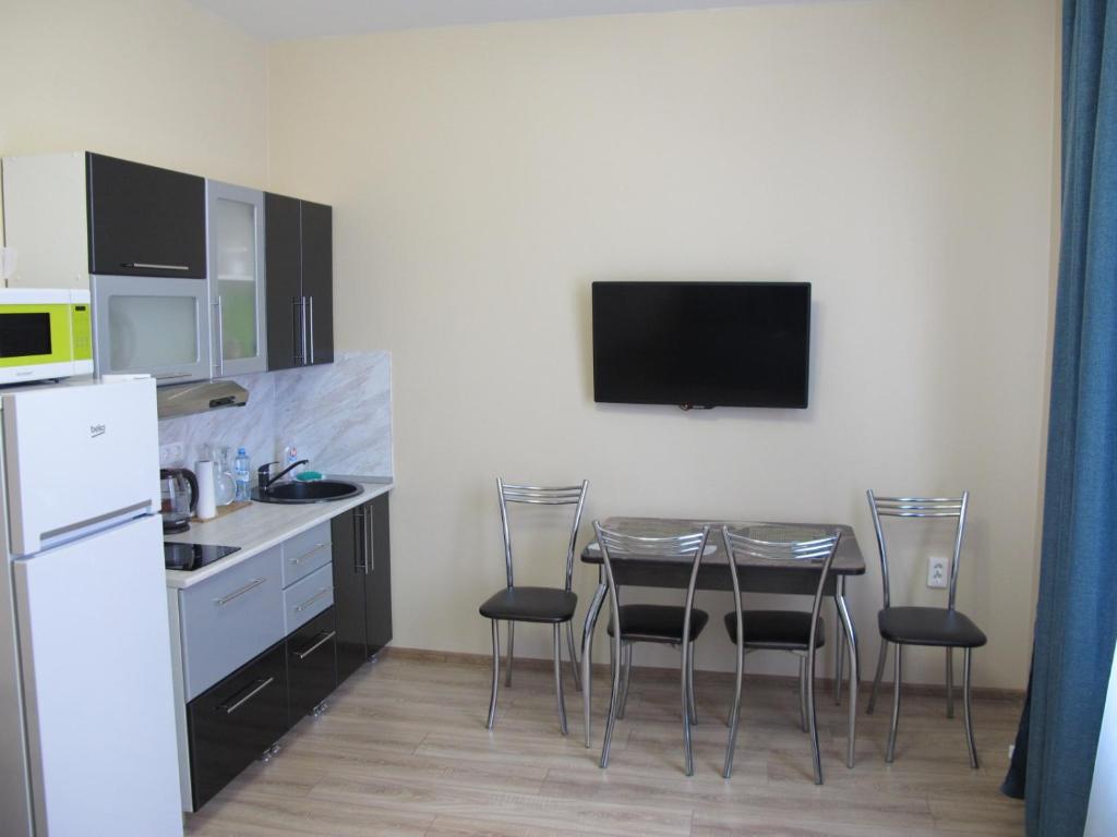 a kitchen with a table and chairs and a tv at Apartament Shkiperskaia 9 in Adler