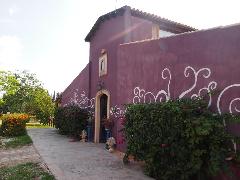 een paars huis met een paarse muur met bloemen bij Agrib&B Lemontree Garde'N in Siracusa