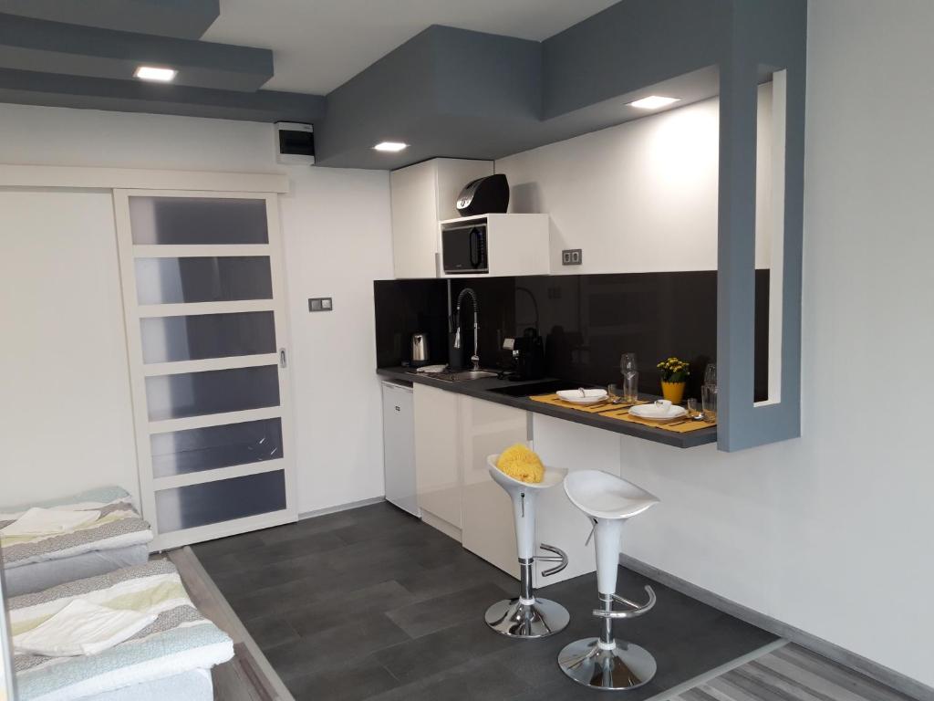 eine Küche mit einer Theke und Hockern in einem Zimmer in der Unterkunft Belvárosi apartman in Szigetvár