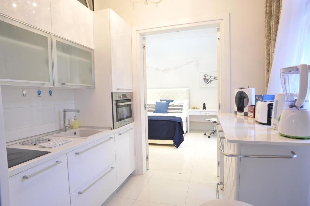a kitchen with white cabinets and a room with a bed at Arum-Lily in Zagreb
