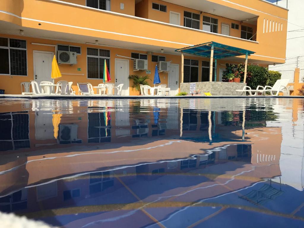 una piscina con sillas y un edificio en HOTEL SUNSHINE AIRE ACND y WIFI ZONE en Tonsupa