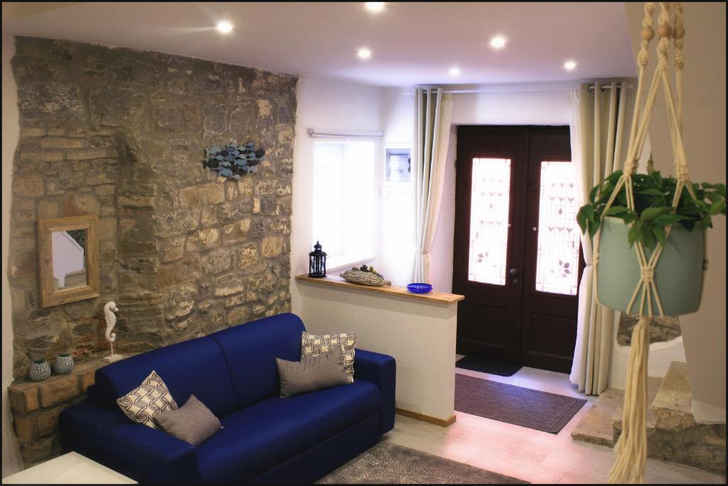 Casa Vacanze Enjoy Pirano في بيران: غرفة معيشة مع أريكة زرقاء وجدار حجري