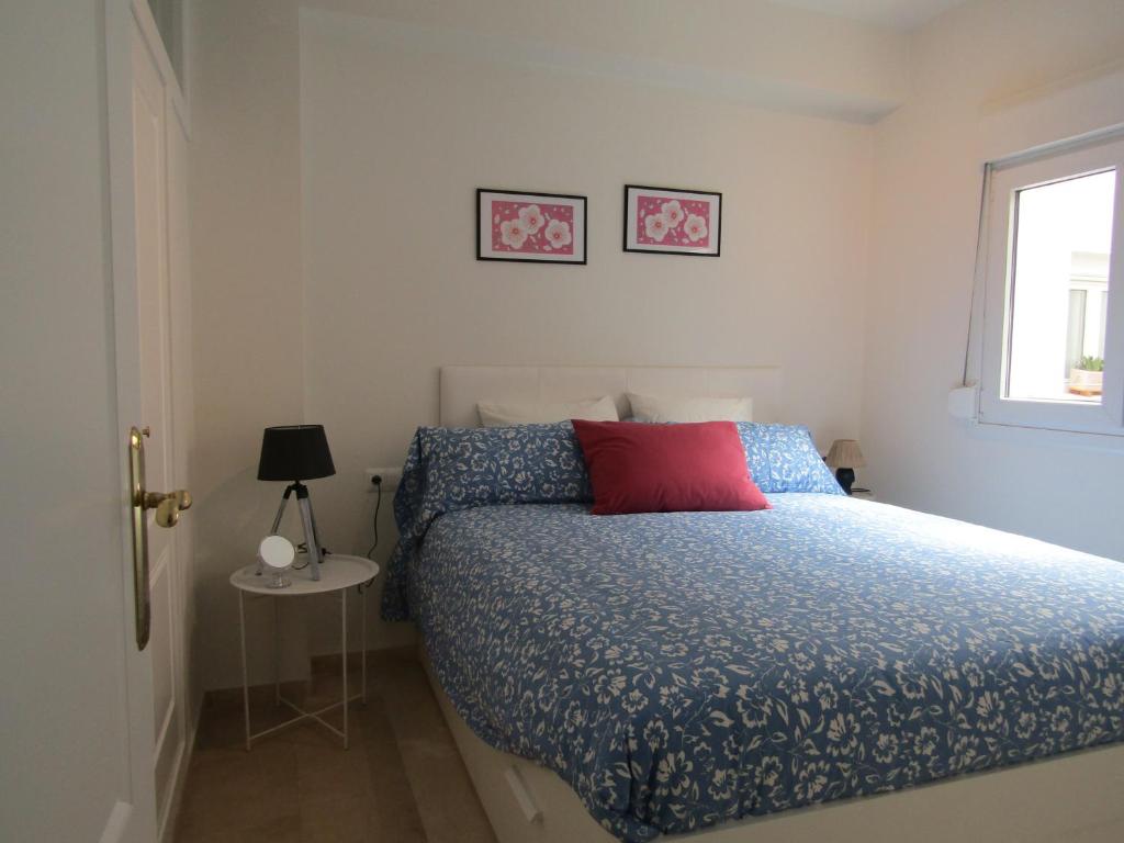 um quarto com uma cama com uma almofada vermelha e uma janela em Apartamento AGP Centro Histórico em Málaga