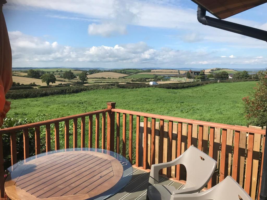 terraza de madera con mesa y sillas en el balcón en Drumlin View Cabin 21c Deerpark Road, en Ardkeen