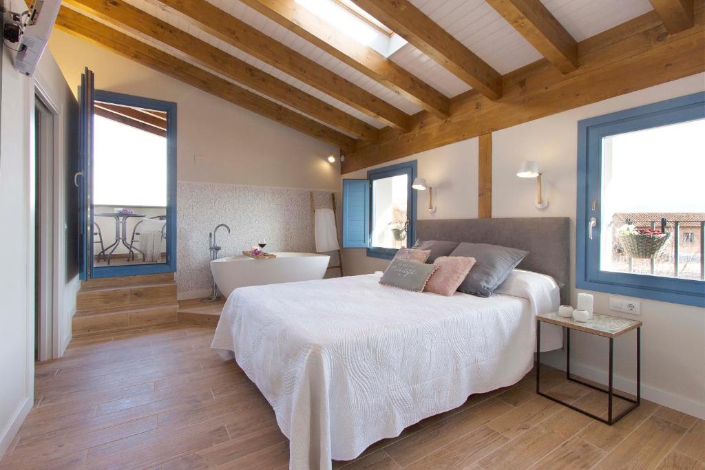 a bedroom with a bed and a tub and windows at El Mirador de Eloísa in Rodezno